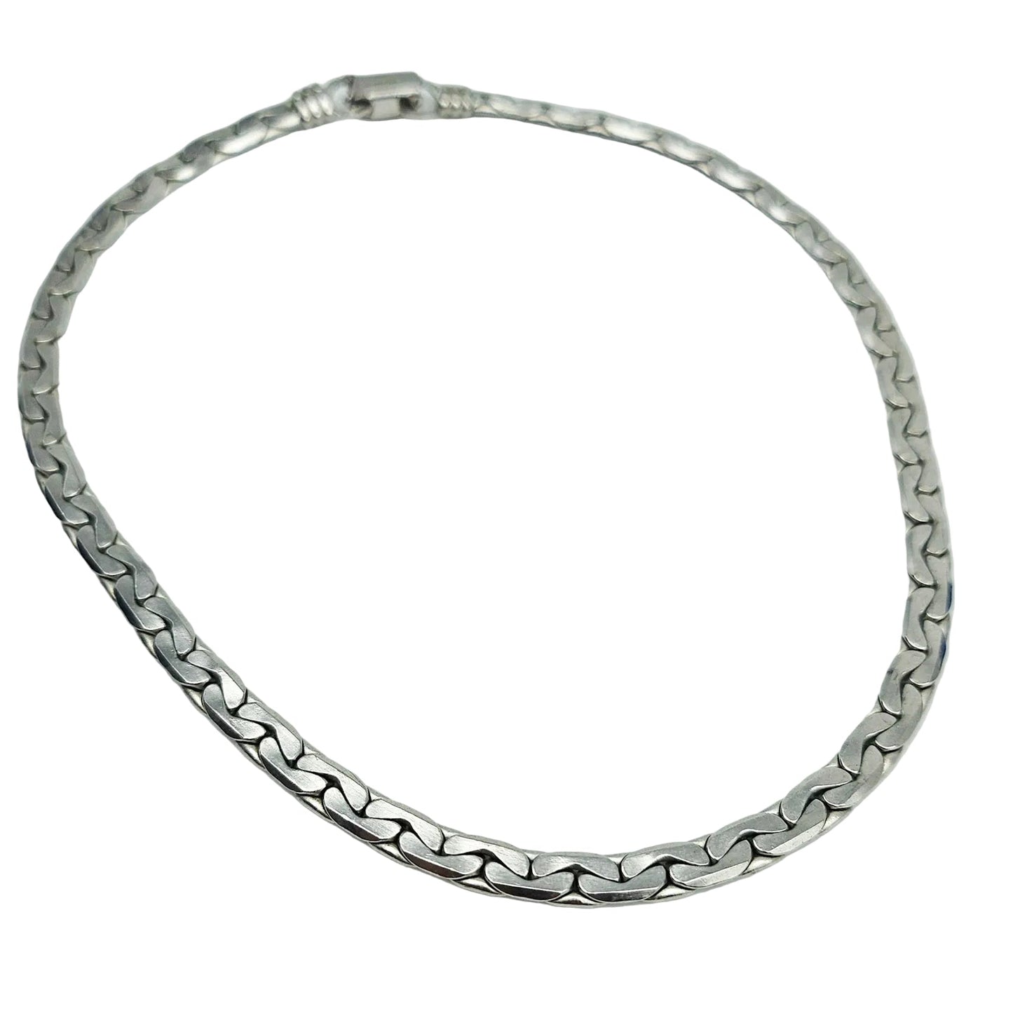 A silver-toned metal chain necklace with a curb-style link pattern, arranged in a circle on a plain white background.
