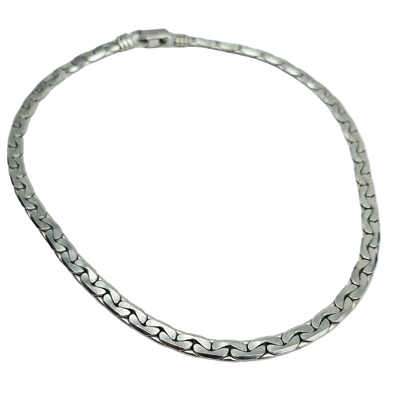 A silver-toned metal chain necklace with a curb-style link pattern, arranged in a circle on a plain white background.