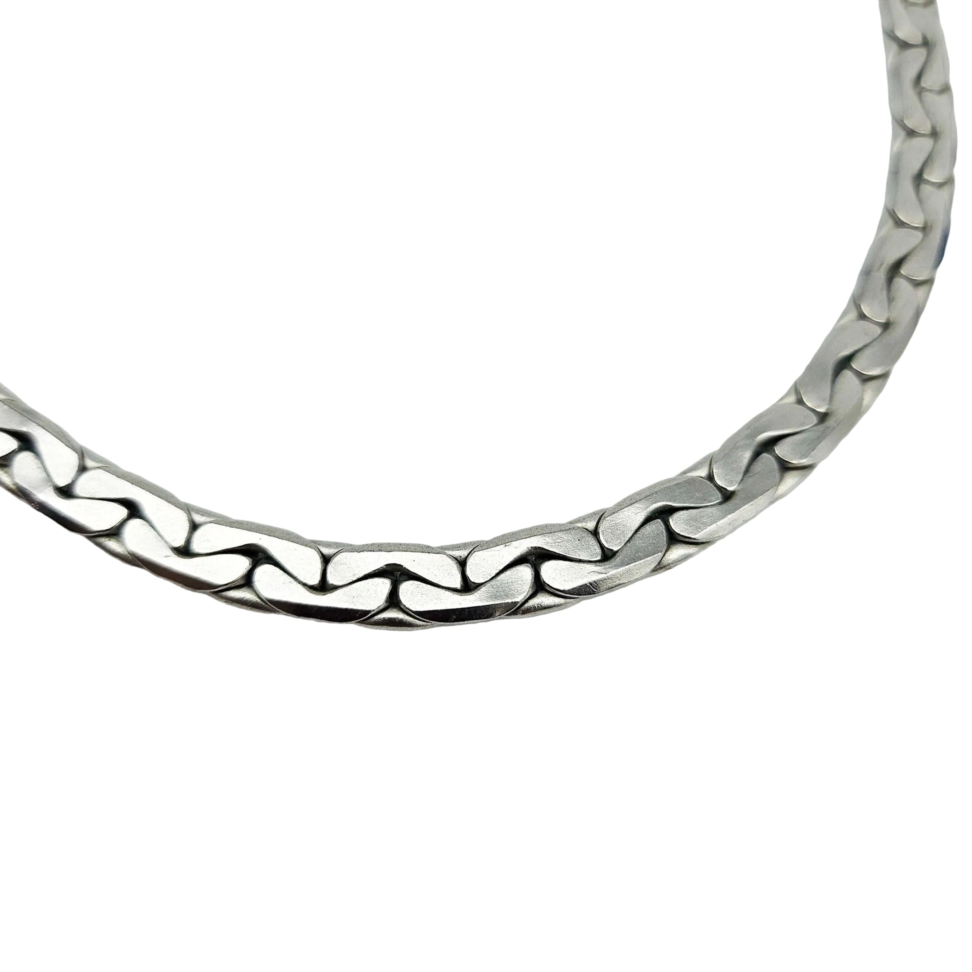 A close-up of a silver-toned metal chain necklace with a wavy, interlocking link design, photographed against a plain light gray background.