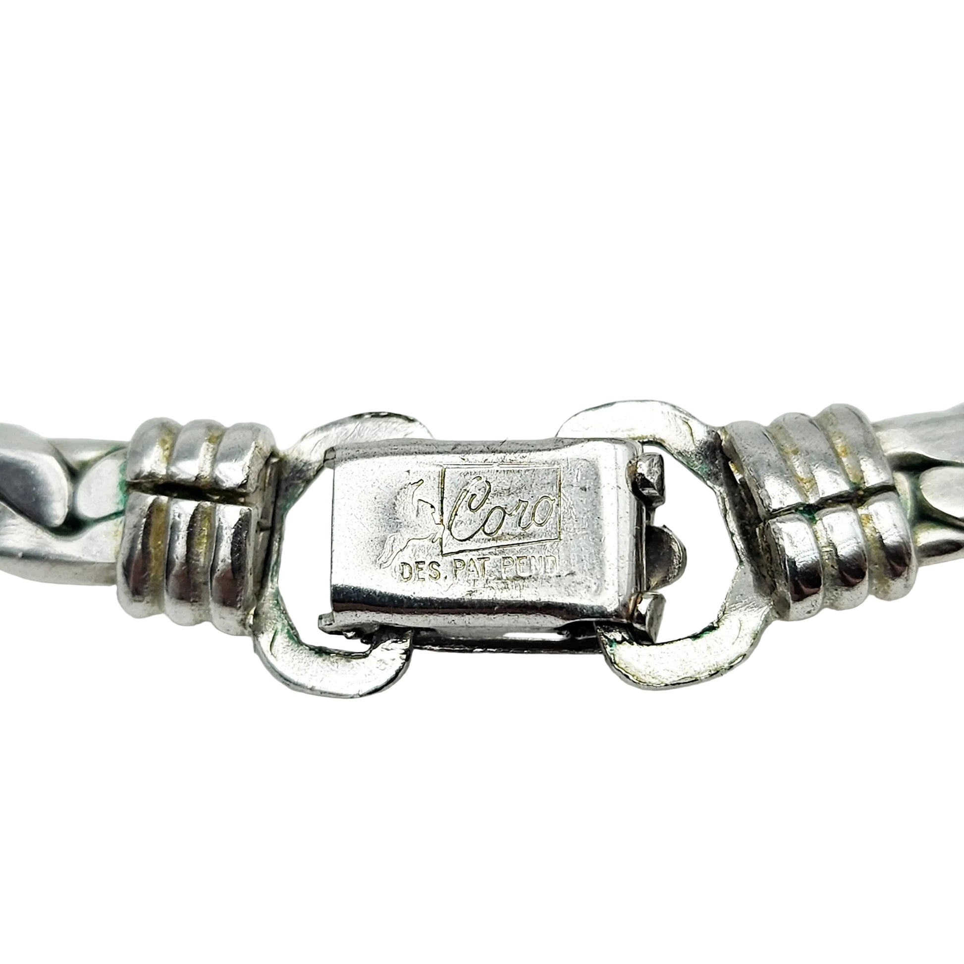 Close-up of a silver-tone metal bracelet clasp showing the engraved brand name 'Cord' and 'DES. PAT.